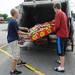Oleg Lougheed, 19, and Nate Wegryn, 17, load a box of ruined fireworks into the back of a garbage truck as they work to clean up after storm damage at Jake's Fireworks on Thursday morning.  Melanie Maxwell I AnnArbor.com